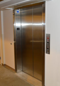 Elevator door with a wide entrance and hall station in hoistway wall.